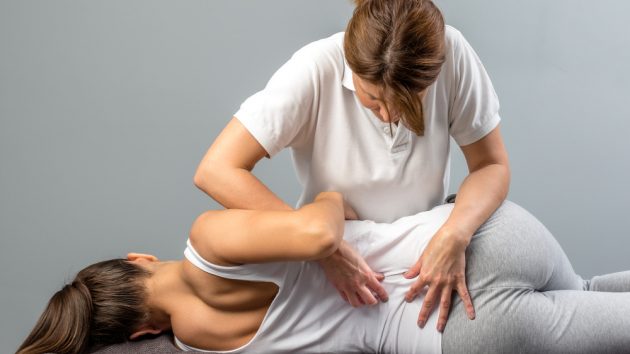 image of a Female physiotherapist doing manipulative spine treatment on young patient